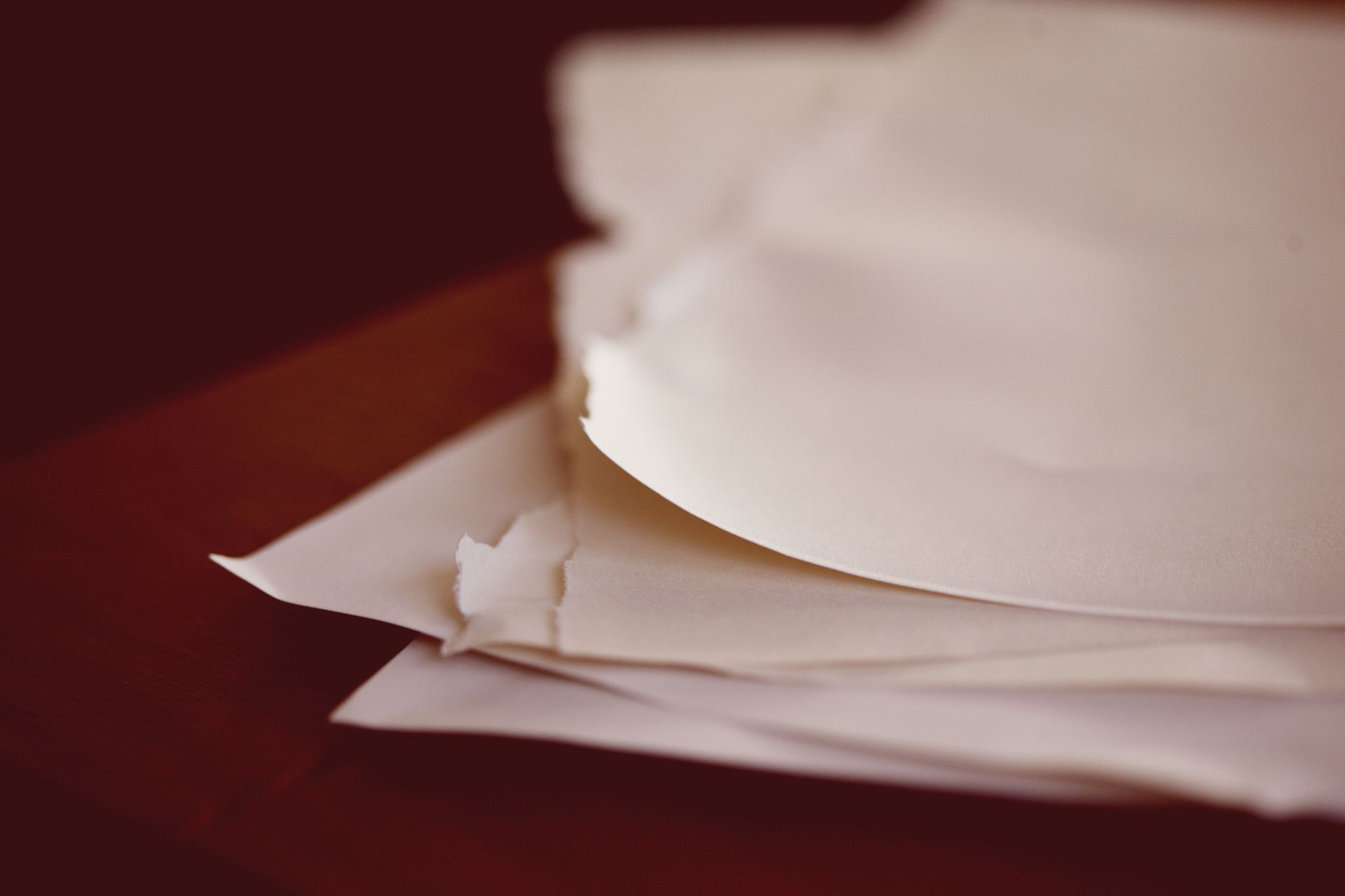 A close-up view of torn papers stacked on a desk with a blurred background.